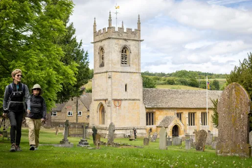 Two women walking on a grass field with a palace building in the background