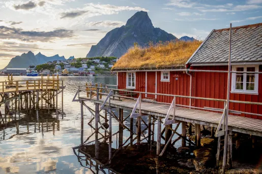 Red building in front of a large lake, with mountains in the distance