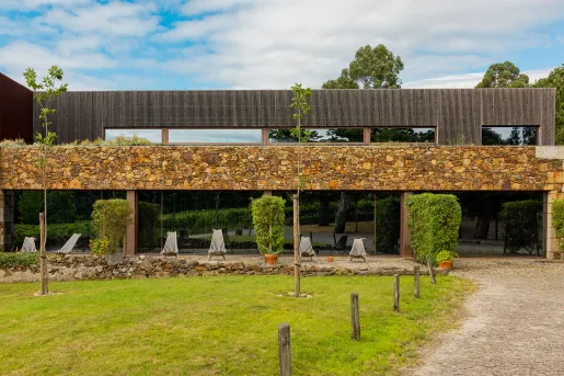 Exterior view of a modern stone and wood building, with a grass area in front