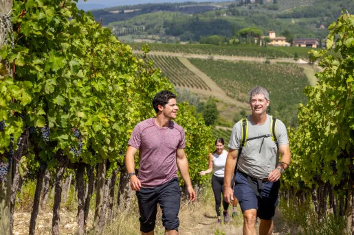 Two men smiling while walking through a crop field in the middle of a valley