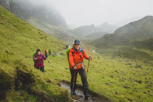Group of people with walking poles, hiking along a mud and dirt trial
