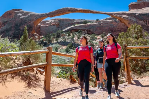Group of women walking through a dirt trail surrounded by mountains and large canyons