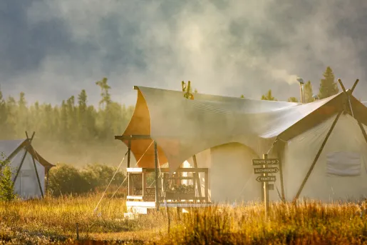 Luxury, white tent surrounded by fog and a forest in the background