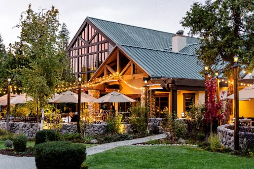 Exterior view of wooden cabin building with large windows, and an outdoor patio