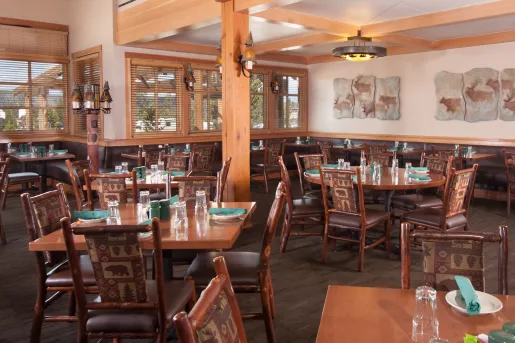 Lodge restaurant with wooden tables and chairs, and paintings on the walls