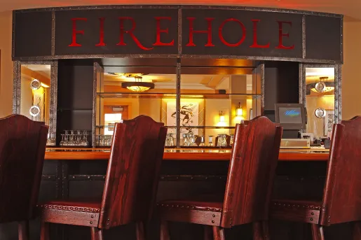 Bar and lounge with wooden stools and a "Firehole" sign above the bar counter
