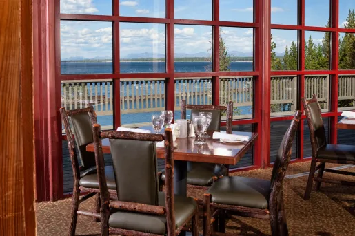 Restaurant dining area with wooden chairs and tables next to large windows