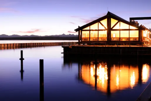 Sunset view of an illuminated building with a lake in front