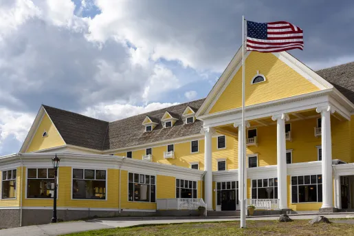 Exterior view of yellow building with an American flag on a flagpole