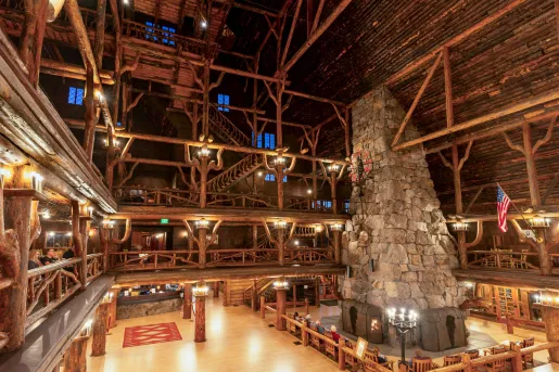 Large cabin with multiple floors and a large stone chimney and fireplace in the center