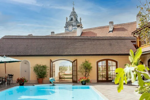 Outdoor pool with a small dolphin statue, and a clocktower in the background