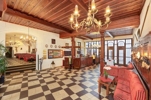 Hotel lobby with large wooden pillars and cushioned sofas over checkered flooring