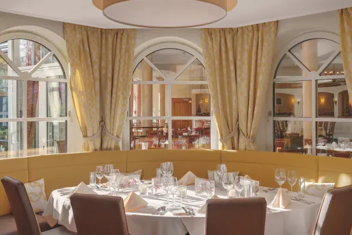 Circular table in a restaurant with wine glasses and folded handkerchiefs in front of each seat