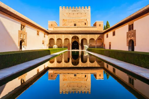 Exterior view of a palace-like building with an outdoor pool in front