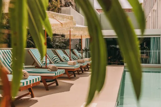 Outdoor pool with white and blue striped chairs and white umbrellas