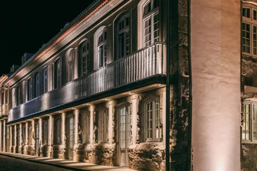 Evening, exterior view of stone hotel building with exposed brick walls