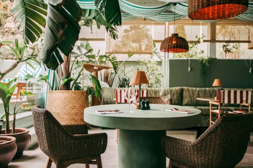 Outdoor patio and dining area with a green, circular table and woven chairs