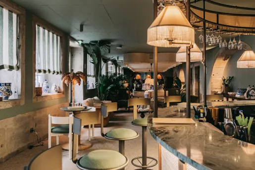 Bar and lounge with a marble countertop and green, cushioned bar stools