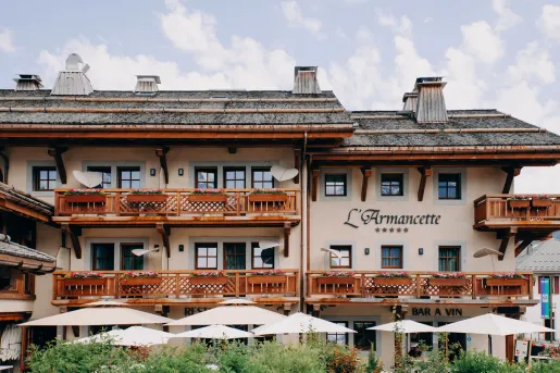 Exterior view of beige and brown hotel building, white beige umbrellas in front