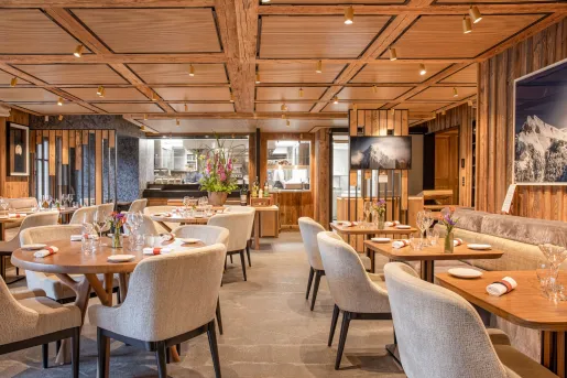 Indoor restaurant with beige, cushioned chairs and wooden tables