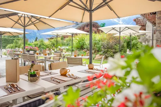 Outdoor patio with long, white dining tables and beige umbrellas