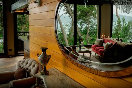 A large round mirror perfectly captures the lakeside sitting area, framed by native Patagonian trees outside at the Calfuco Wine Hotel & Spa in Neuquén, Argentina.