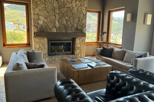 Lounge seating area with cushioned, beige couches in front of a stone fireplace