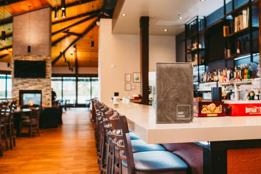 Bar and lounge with white counter and alcohol on shelving along the walls