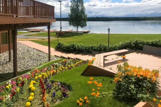 Grass field with garden next to a building, with a lake in the background