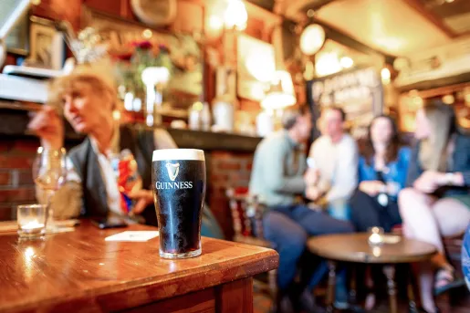 Group of people at a pub, with a full glass of Guinness beer on the tabl