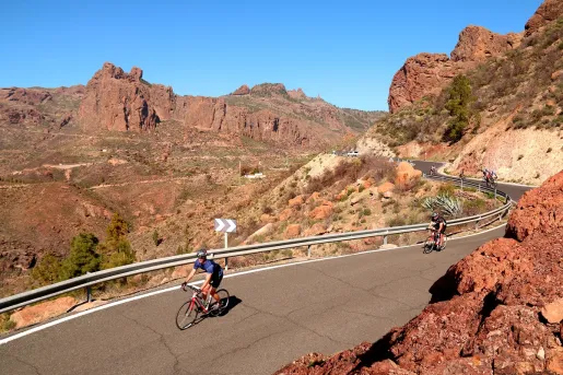 Person biking on a road with large canyons in the background