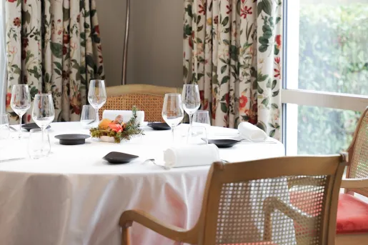 Circular, white dining table with wine glasses and table cloths
