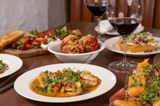 Plates of pasta and other food on a wooden table