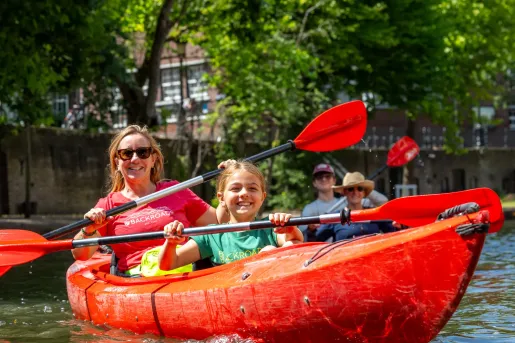 Families kayaking on the scenic canals of Kajaks Korenlei in Ghent, Belgium.