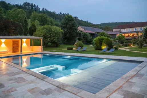 Outdoor pool with lit coverings and large trees in the background