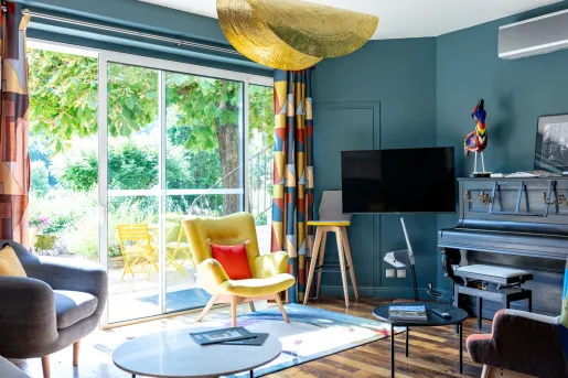 Blue room, with a television mounted on the wall, with a large window looking out to a garden