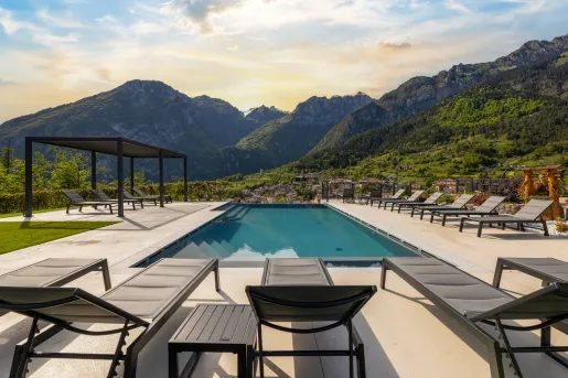 Outdoor pool surrounded by gray chairs with large mountains in the background