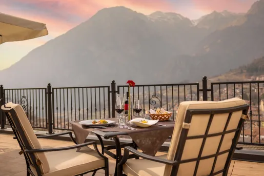 Outdoor patio with a dining table and cushioned chairs with mountains in the distance
