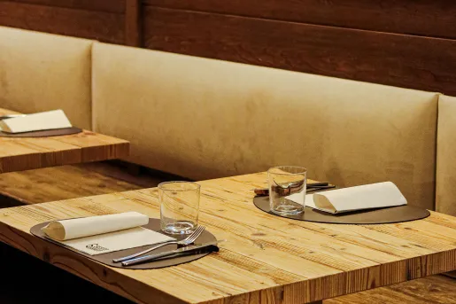 Wooden dining table with handkerchiefs, silverware and glasses on the table