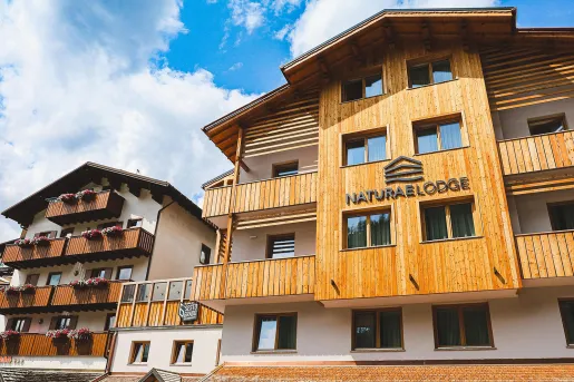 Exterior view of wood and white hotel building with outdoor balconies
