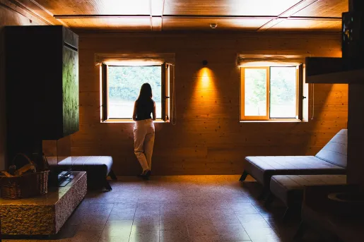 Woman standing in a dimly lit hotel room, looking out an open window