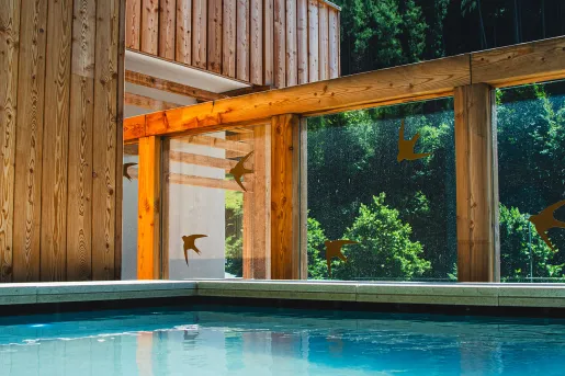 Outdoor pool with large, wooden pillars and a wooden lodge to the left