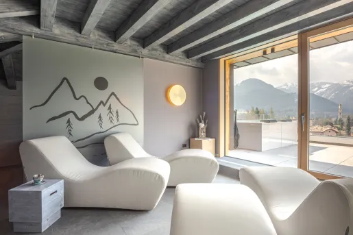 White, reclining lounge chairs looking out towards two glass doors looking towards tall mountains