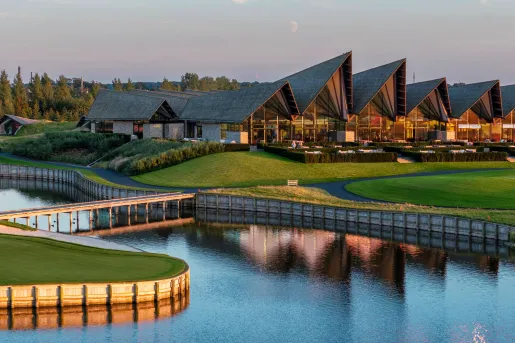 Exterior, evening view of hotel building with a grass lawn and large lake in front