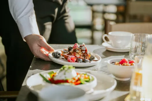 Waiter serving a plate of food onto a white table