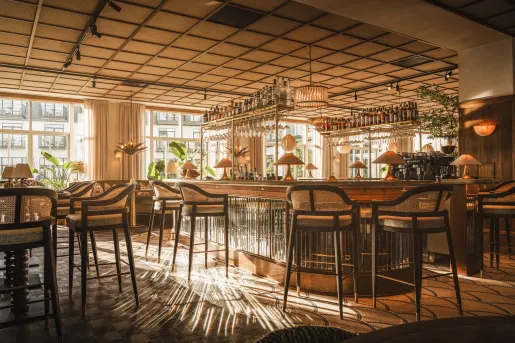 Indoor bar and lounge with tall stools and shelves holding bottles of liquor