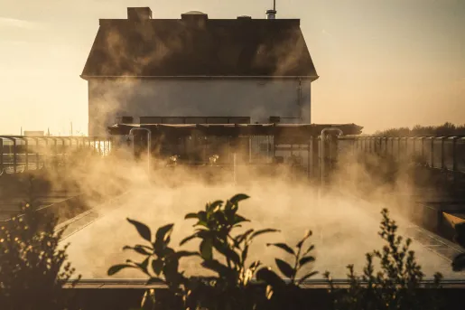 Outdoor pool with steam coming out with a large building in the background