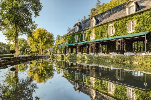 The exterior ivy-covered stone facade of Manoir d'Hautegente hotel in Coly-Saint-Amand, Dordogne.