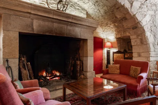 Lounge seating at Manoir d'Hautegente features red sofas, a stone fireplace, and a vaulted ceiling.