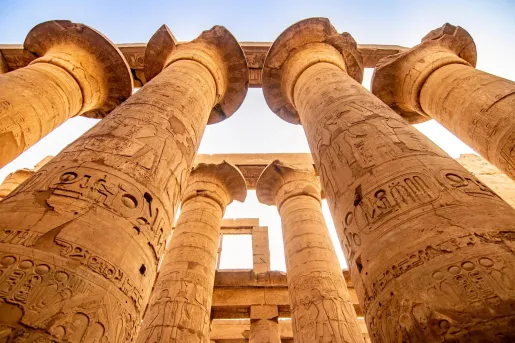 The Great Hypostyle Hall within the Karnak Temple complex in Luxor, Egypt featuring massive columns with hieroglyphics, and ancient symbols. 